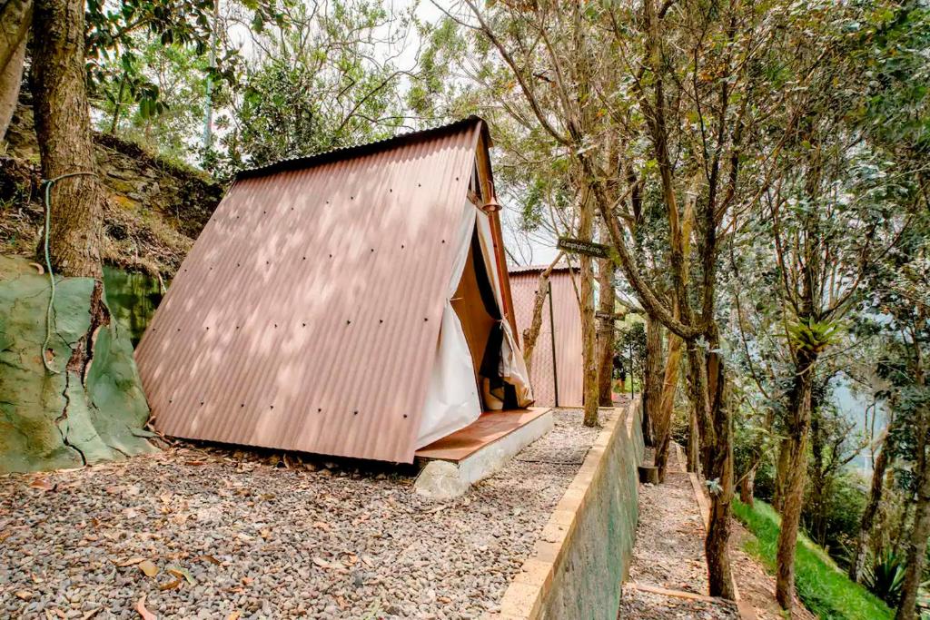 a small house with a brown roof in the woods at Refugio Explora Verde in Choachí