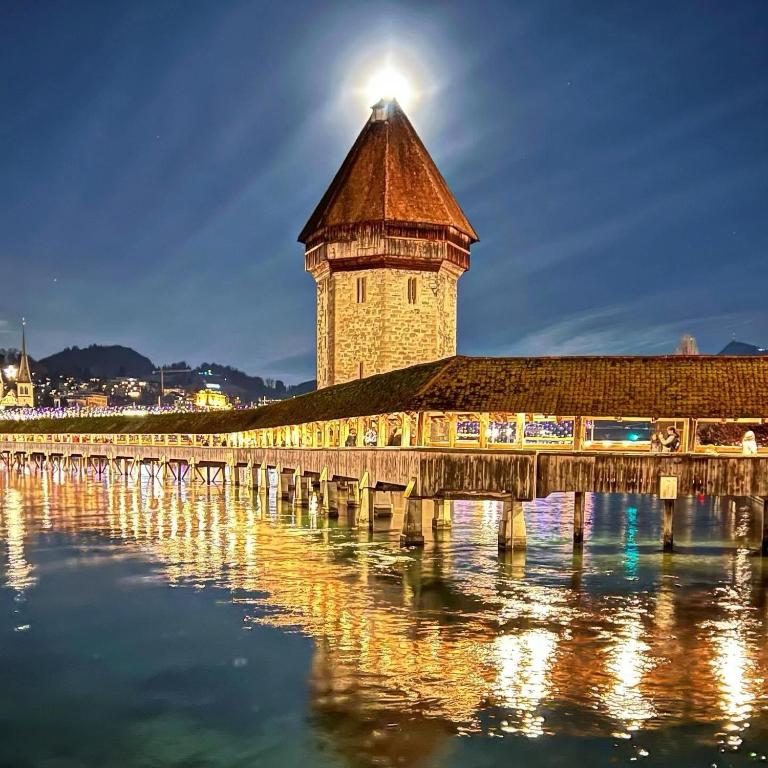 a lighthouse on a bridge over water at night at Ooooo in Lucerne