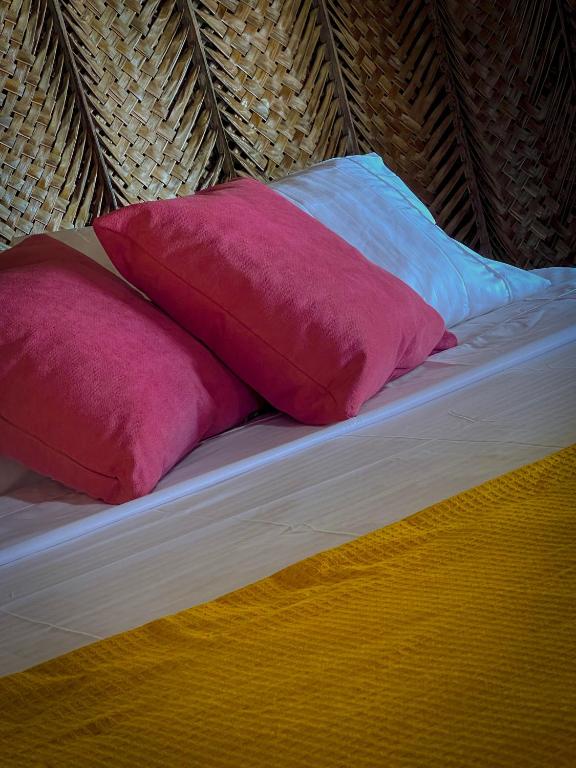 a bed with three colorful pillows on it at Los Achiotes Hostal - Palomino in Palomino