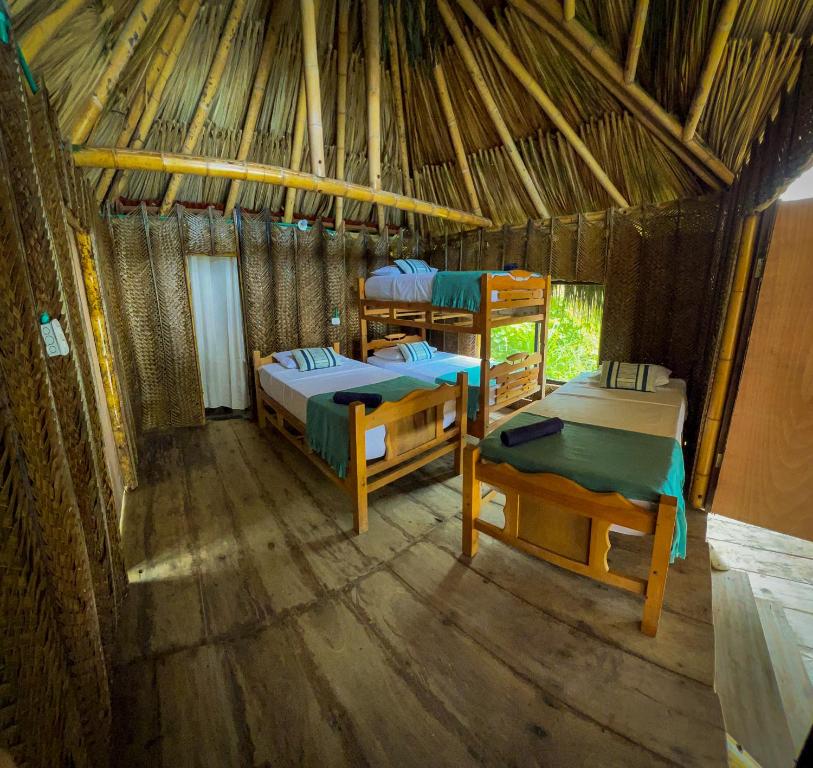 a room with two beds in a straw hut at Los Achiotes Hostal - Palomino in Palomino