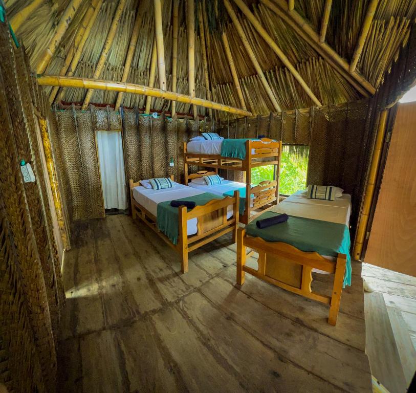 a room with two beds in a straw hut at Los Achiotes Hostal in Palomino