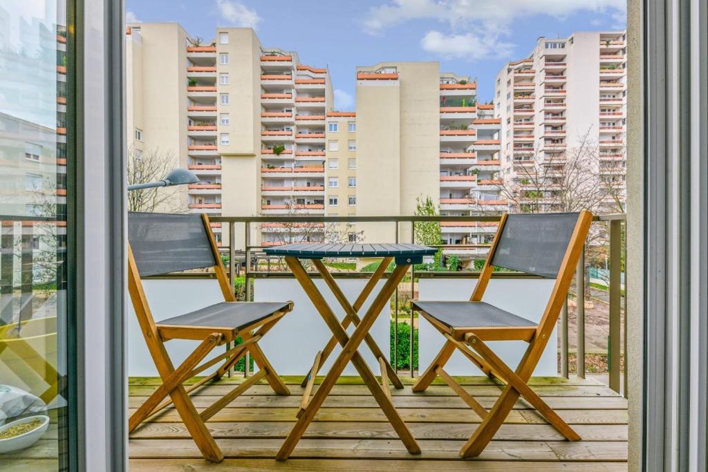 2 chaises et une table sur un balcon avec des bâtiments dans l'établissement Appartement Ollier - Welkeys, à Villeurbanne