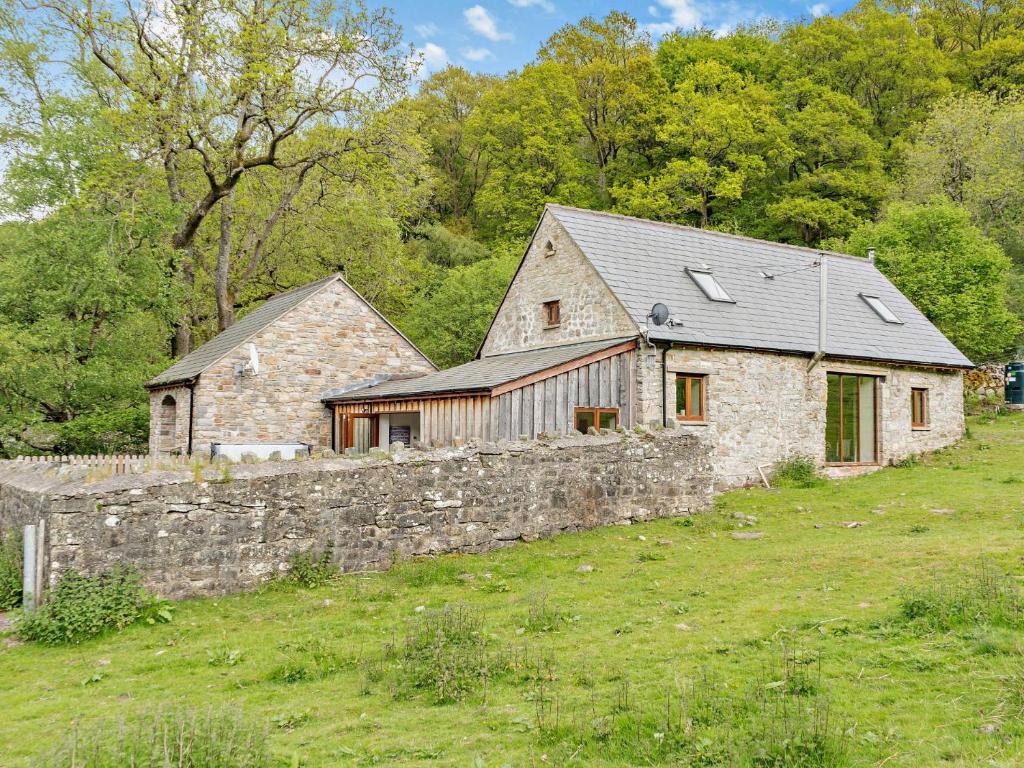 a stone house in a field with a stone wall at 3 Bed in Govilon 59730 in Govilon