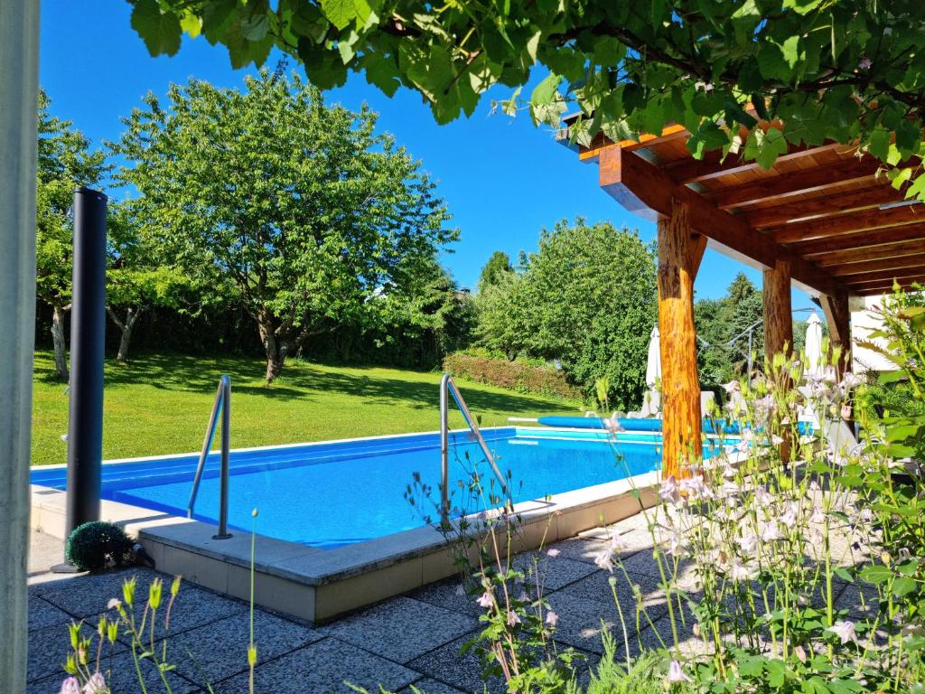 a swimming pool in a garden with a pergola at Apartments Presslauer - Mori in Sankt Kanzian