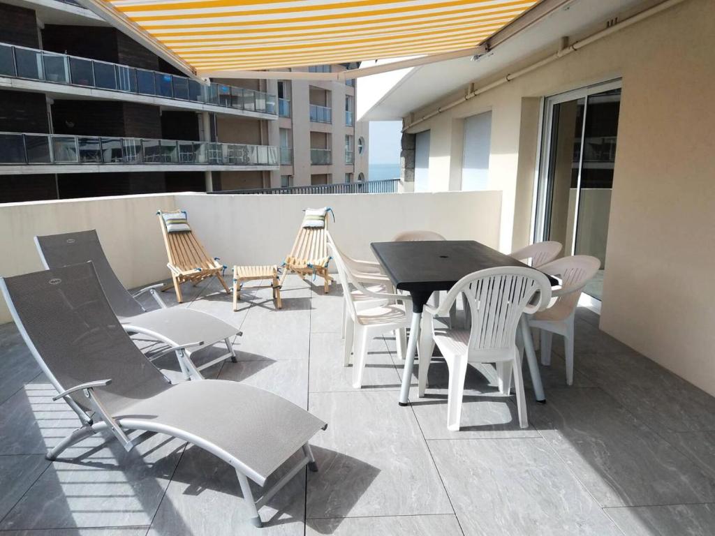 un patio avec une table et des chaises sur un balcon dans l'établissement Résidence Casino - Charmant T3 en plein cœur de la station balnéaire du Val-André. MAE-6444, à Pléneuf-Val-André