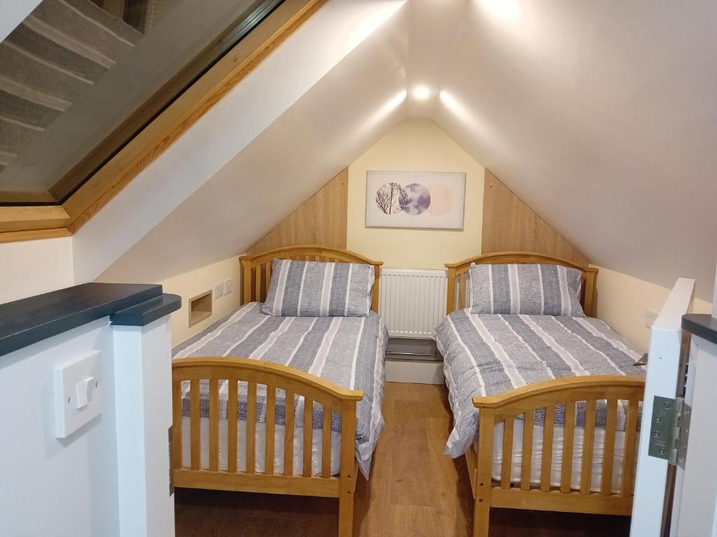 two beds in a attic room with stairs at Fenniscourt Cottage in Carlow