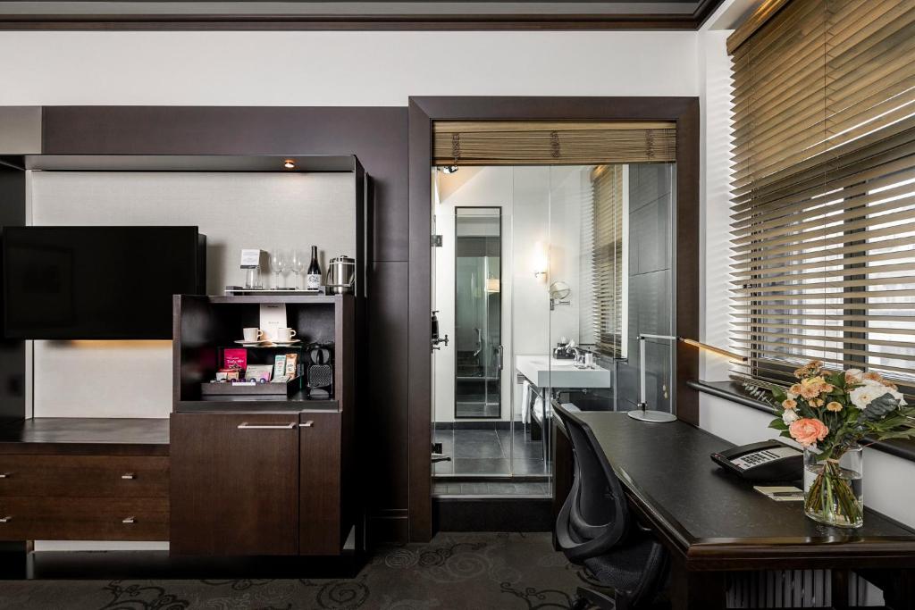 a living room with a desk and a television at Hôtel Le Germain Québec in Quebec City