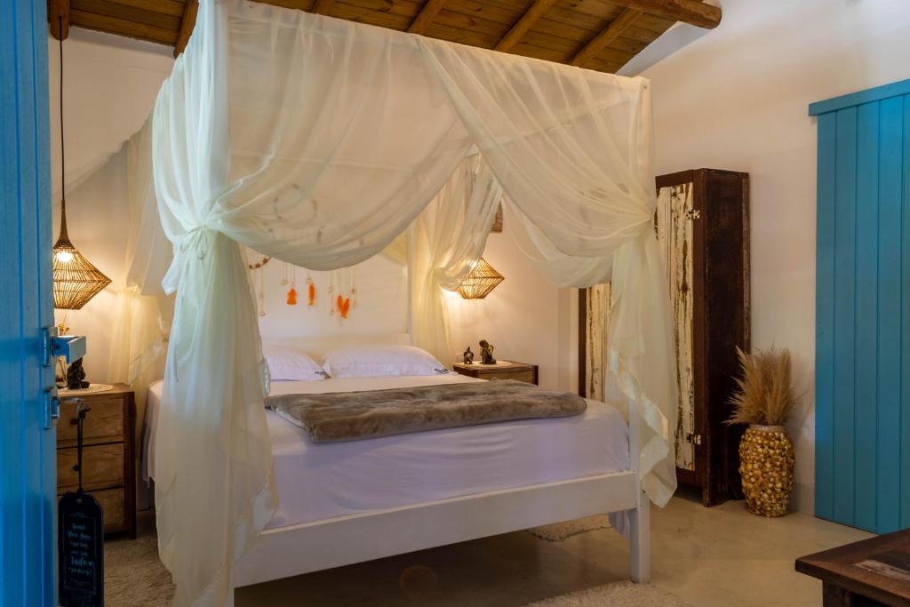 1 dormitorio con cama con dosel y cortinas blancas en Suite DAVI - Guest House Guaiu en Santa Cruz Cabrália