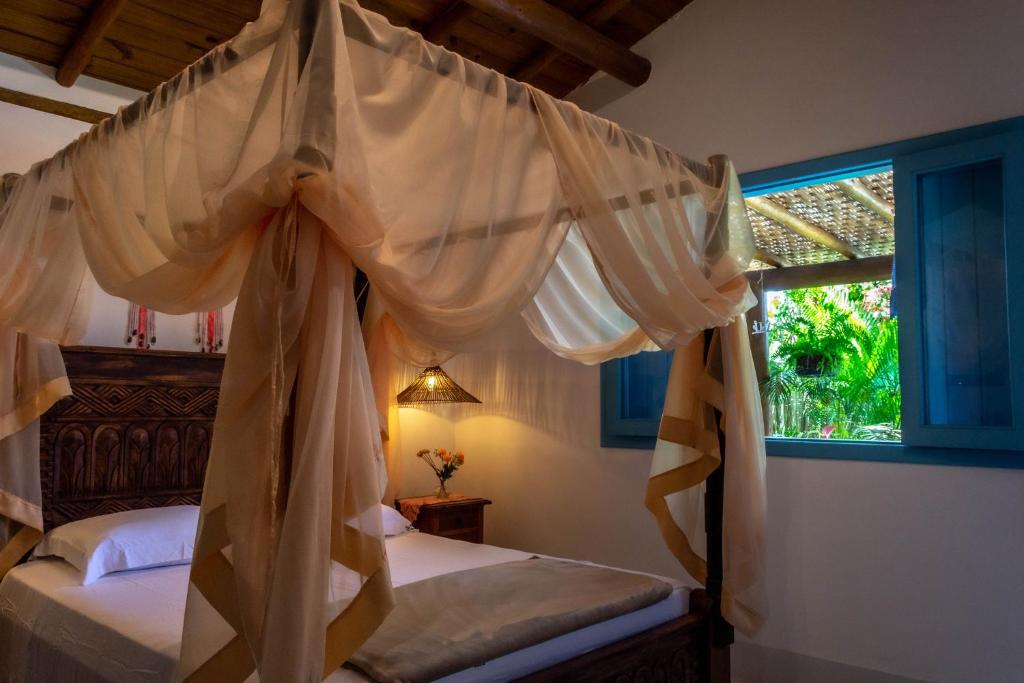 a bedroom with a canopy bed and a window at Suite NOAH - Guest House Guaiu in Santa Cruz Cabrália