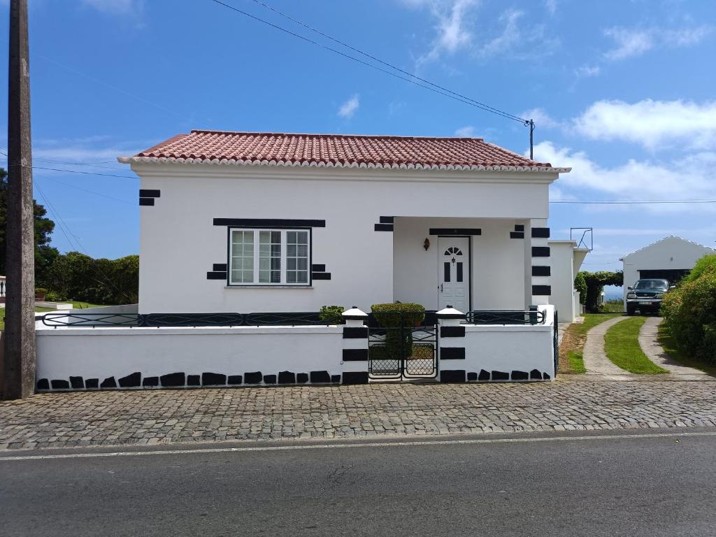 ein weißes Haus mit rotem Dach auf einer Straße in der Unterkunft Casa da Atalaia in Angra do Heroísmo