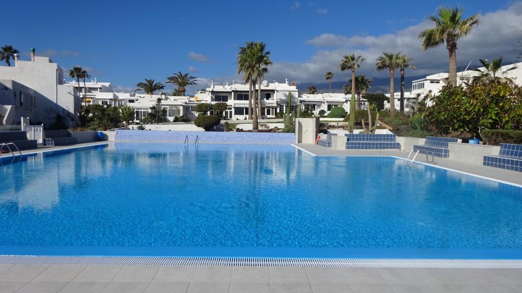 ein großer Pool mit Palmen und weißen Gebäuden in der Unterkunft Ferienwohnung mit Dachterrasse, mehreren Pools, Garten und viel Ruhe in Poris de Abona
