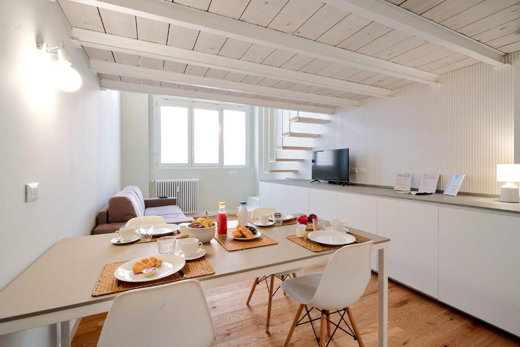MILAN design Loft-Hosted by Sweetstay في ميلانو: مطبخ وغرفة طعام مع طاولة وكراسي
