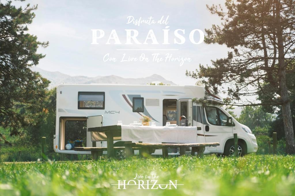 une caravane blanche garée dans un champ avec une table dans l'établissement Live On The Horizon 1, à Ribadesella