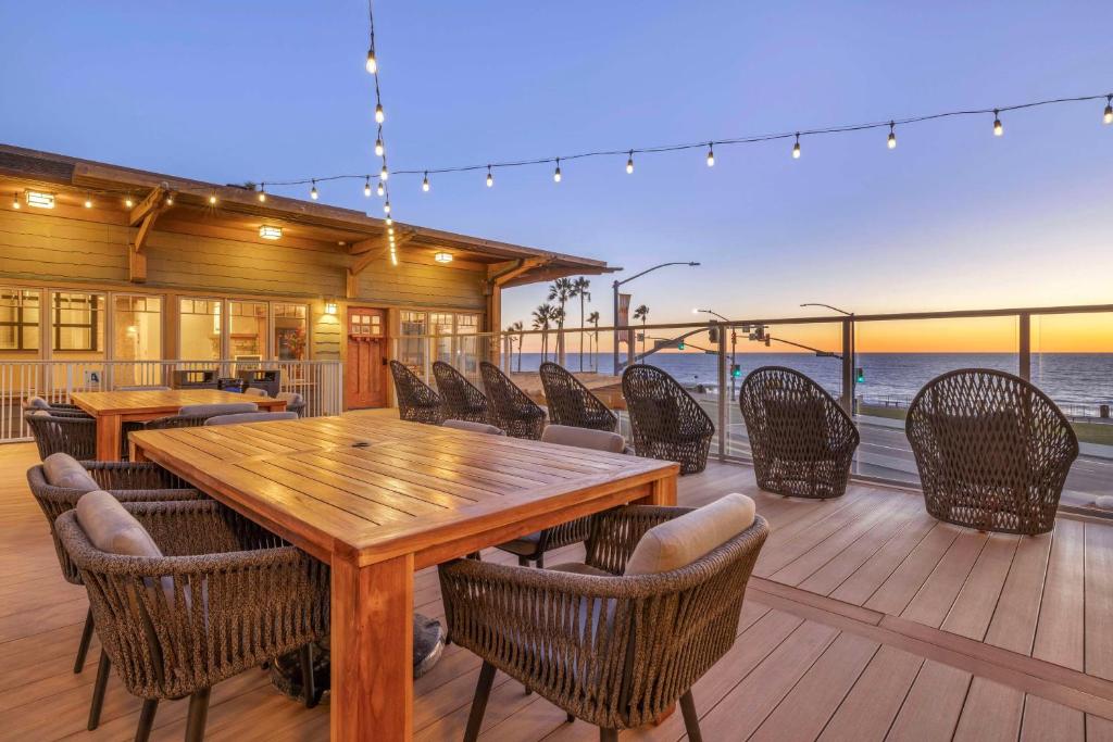 una mesa de madera y sillas en una terraza con vistas al océano en Best Western Plus Beach View Lodge, en Carlsbad