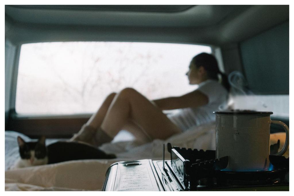 a woman sitting on a bed looking out a window at Live On The Horizon 2 in Ribadesella