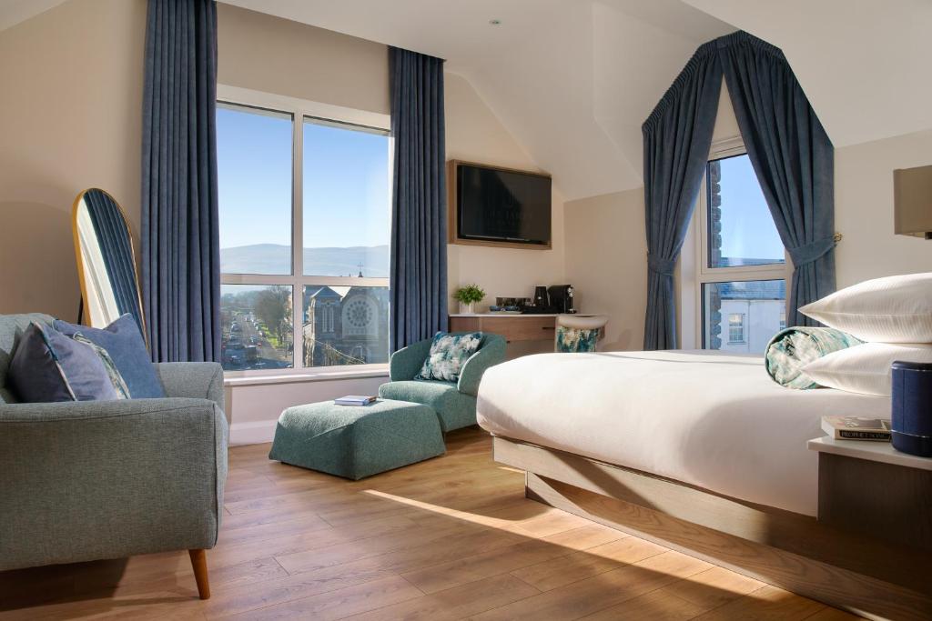 een slaapkamer met een bed en 2 stoelen en een groot raam bij The James Hotel in Tralee