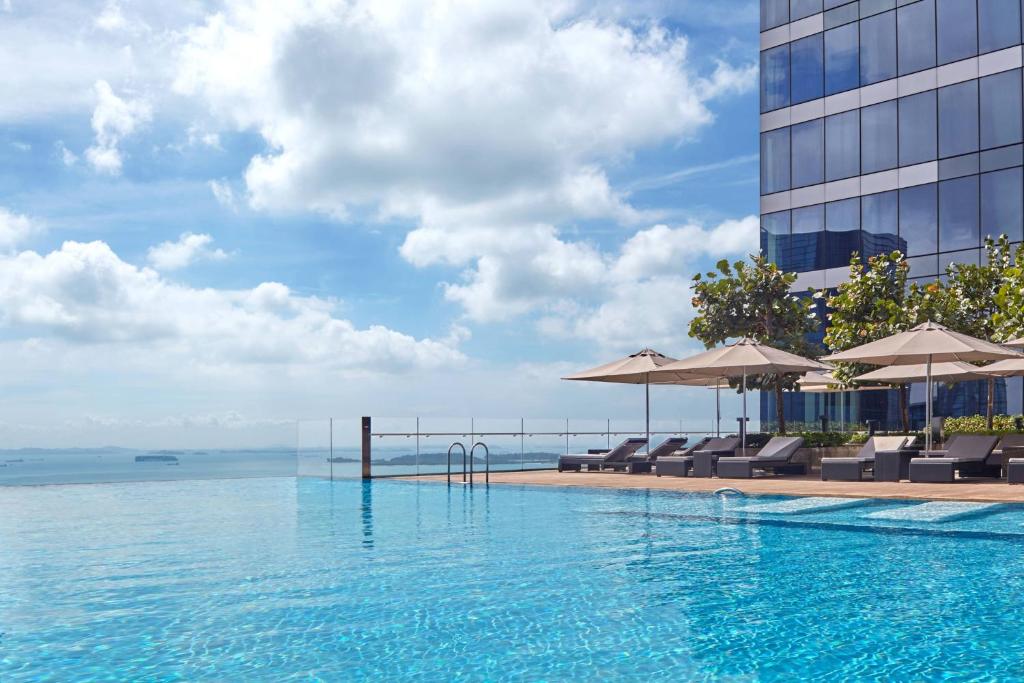 una piscina con sedie e ombrelloni accanto a un edificio di The Westin Singapore a Singapore