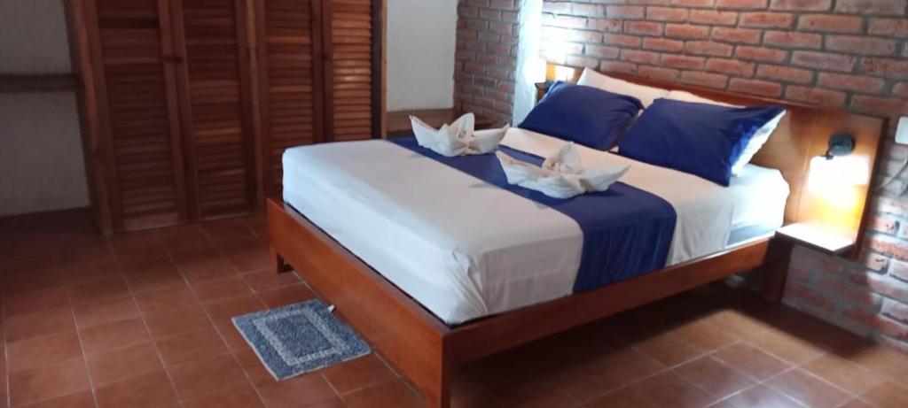 a bedroom with a large bed with blue pillows at Hosteria Cumilinche in Same