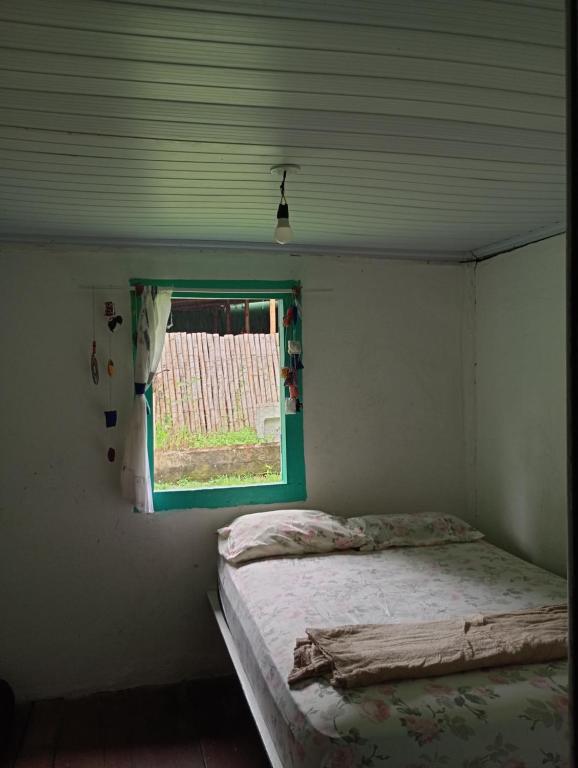 1 dormitorio con cama y ventana en Ali Atrás en Macaé