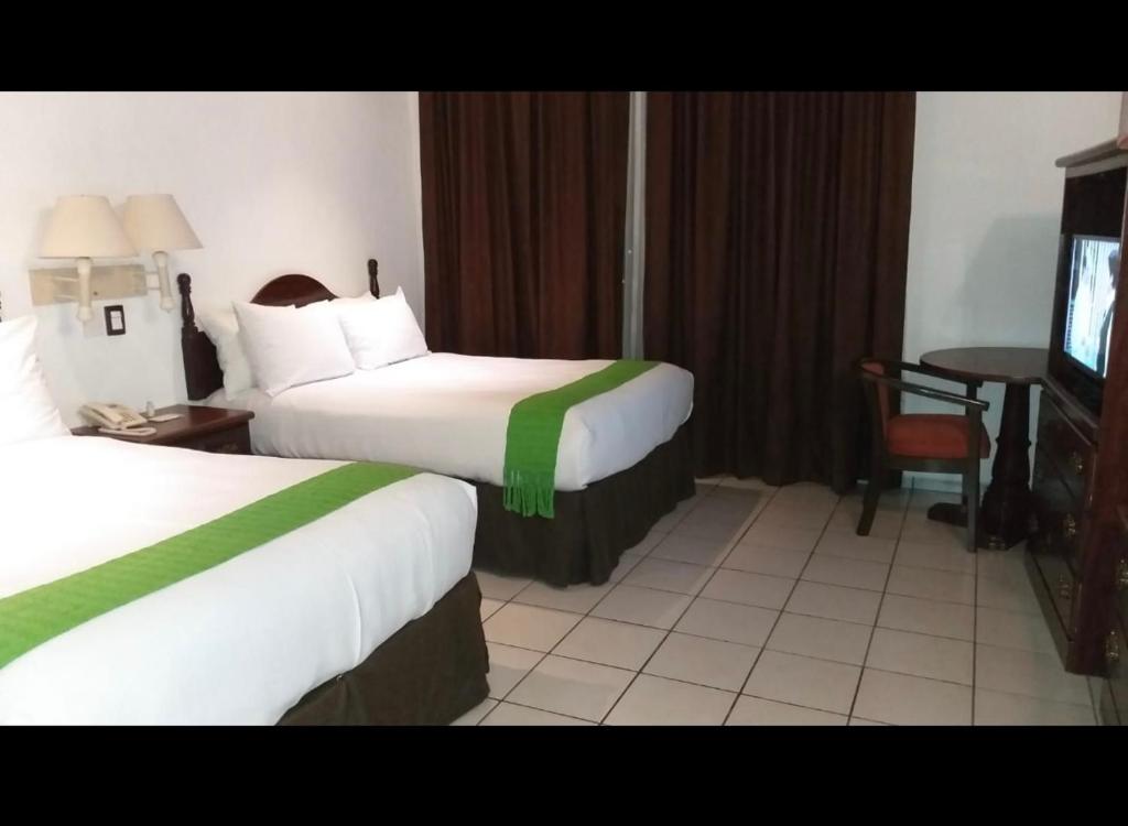 um quarto de hotel com duas camas e uma televisão em HOTEL REAL FLOR DE MARIA em Comitán de Domínguez