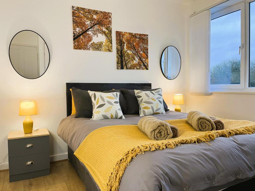 een slaapkamer met een bed met een gele deken en spiegels bij A spacious 3 bedroom house near UHCW, Free parking, Fast Wi-Fi, FHD TV, Netflix, Sleeps up to 9 in Wyken