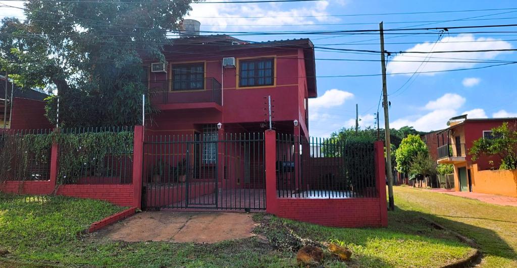 a red house with a red fence at Casa Yvy Pytã in Puerto Iguazú