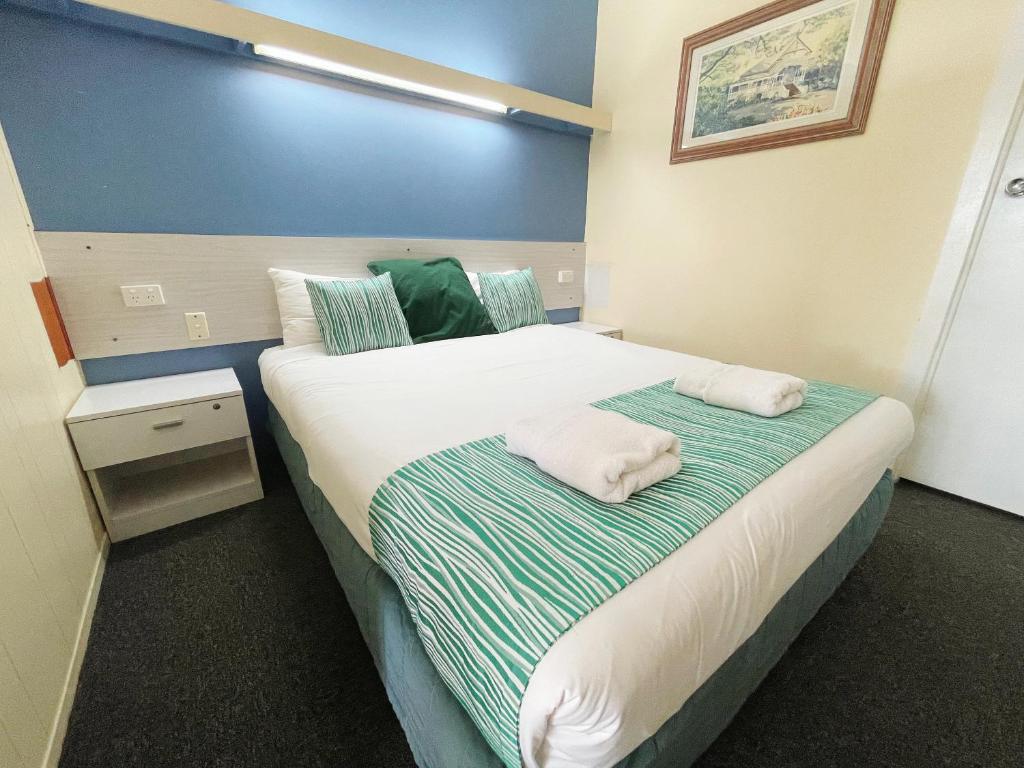 a bedroom with a bed with two towels on it at Arkana Motel in Maryborough