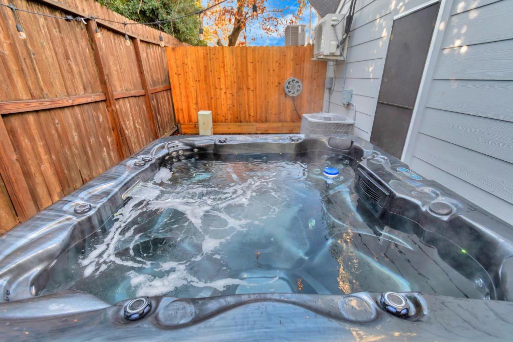 a hot tub in a backyard with a wooden fence at Modern Accessible Houston Gem Jacuzzi & Air Hockey 6Beds in Houston