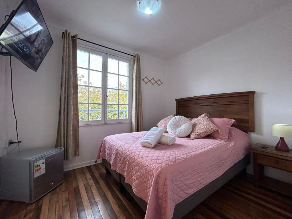 a bedroom with a bed with pink sheets and a window at Casa Di Patti in Santiago