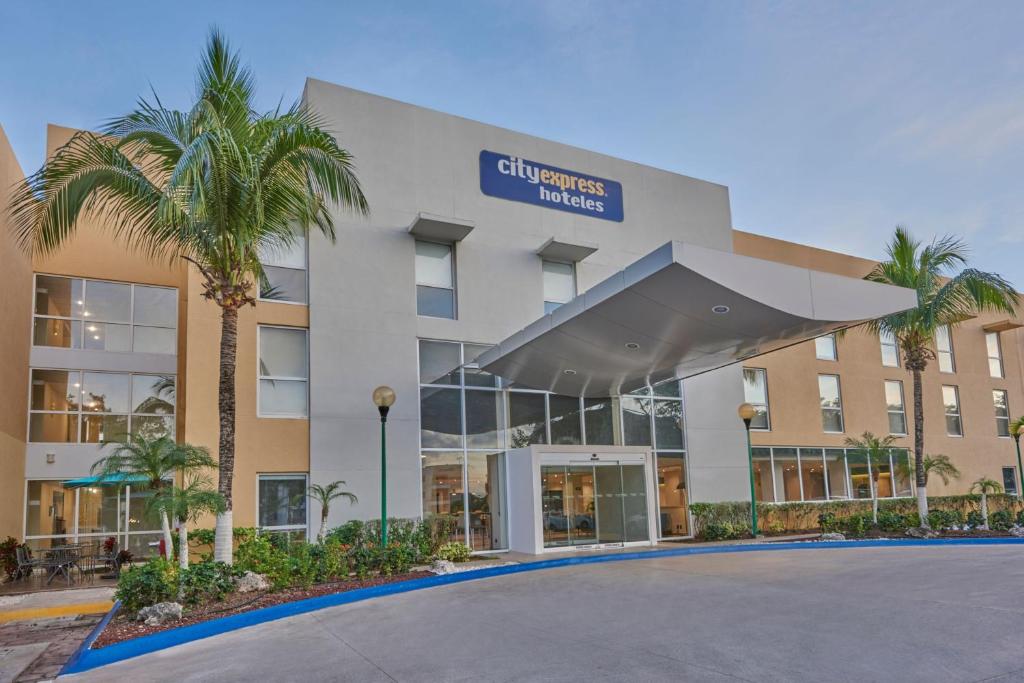 un hotel con una palmera frente a un edificio en City Express by Marriott Playa del Carmen, en Playa del Carmen