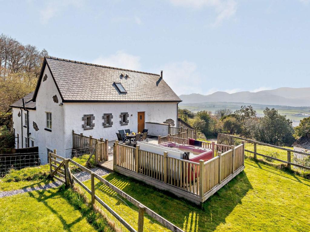 a white house with a wooden fence and a hot tub at 3 Bed in Conwy 74146 in Eglwys-Fâch