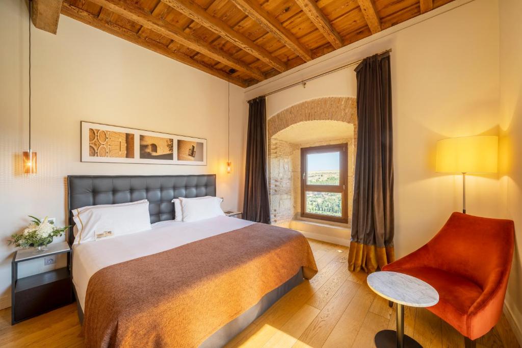 a bedroom with a bed and a chair and a window at Áurea Convento Capuchinos by Eurostars Hotel Company in Segovia