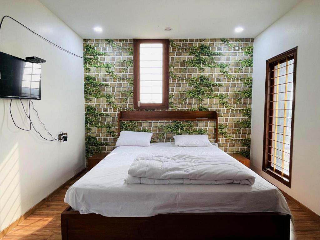 a bedroom with a bed and a wall with plants at Dhruva Service Apartment in Bidadi