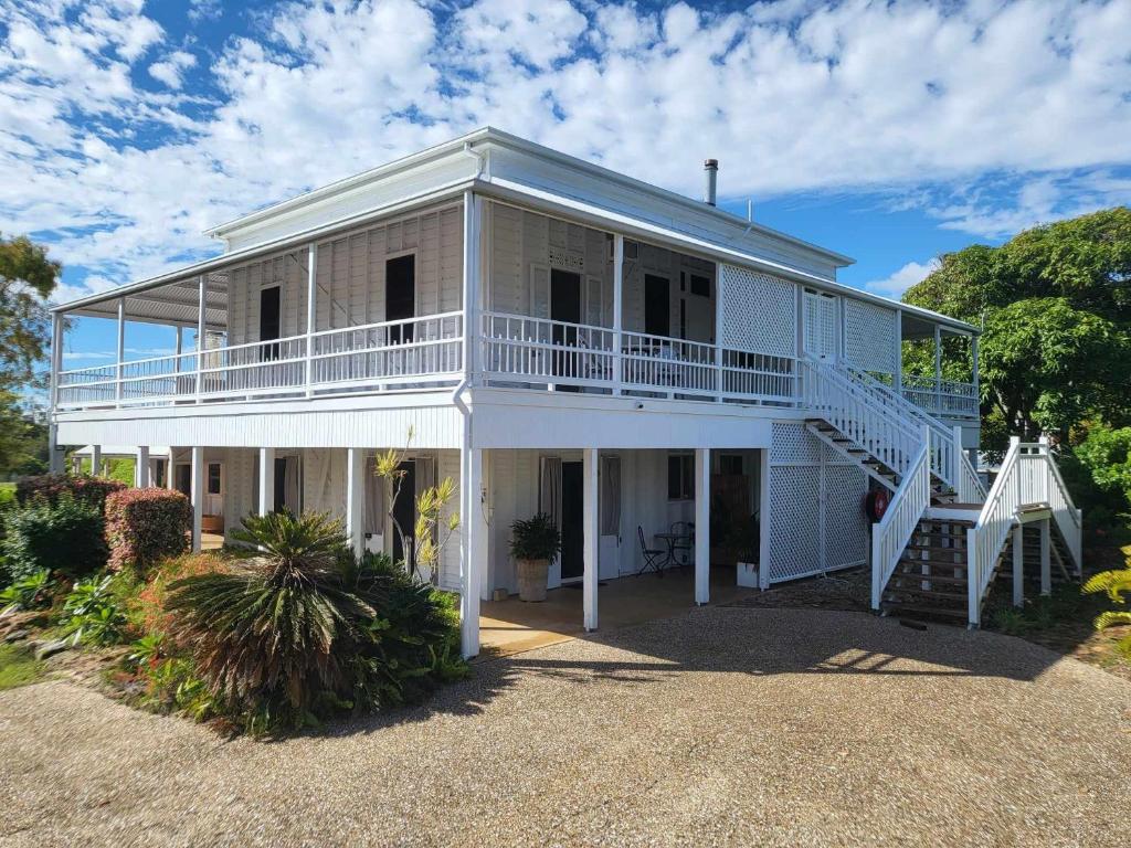 ein großes weißes Haus mit einer Veranda und einer Treppe in der Unterkunft Ribbonwood Bed & Breakfast, Emu Park Qld in Emu Park