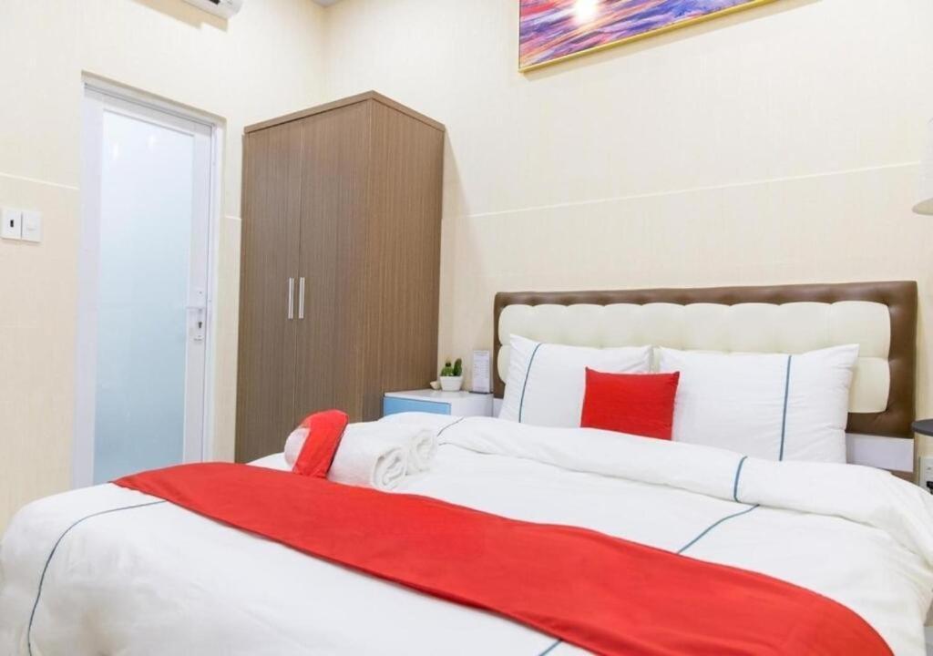 um quarto com uma grande cama branca com almofadas vermelhas em Bro Hotel 45-47 Song Hành, Quận 6 - by Bay Luxury em Ho Chi Minh