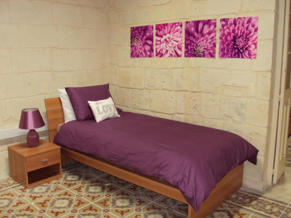 a bedroom with a bed with purple sheets and two paintings at House Valletta in Valletta