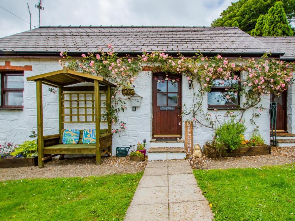 a white house with a pergola filled with flowers at 1 Bed in Narberth 77692 in New Moat