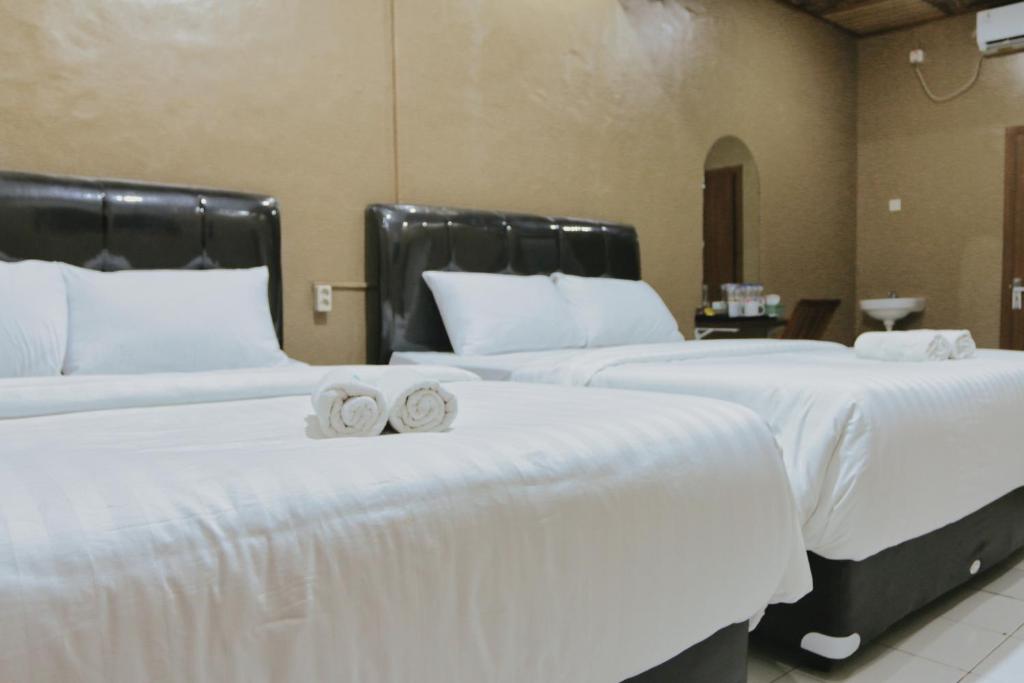 two beds with white sheets and two wedding rings on them at Hotel Solaris Malioboro in Jetis