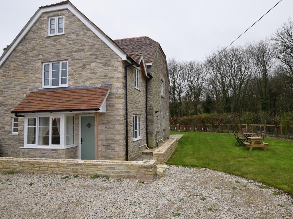 an old stone house with a picnic table in the yard at 4 Bed in Corfe Castle 62985 in Worth Matravers