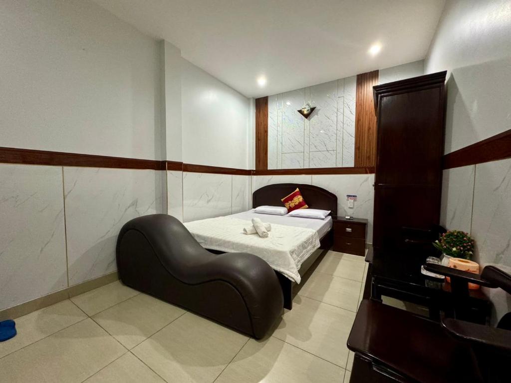 1 dormitorio con 1 cama con silla de cuero negro en Khách Sạn Hoàng Hà en Ho Chi Minh