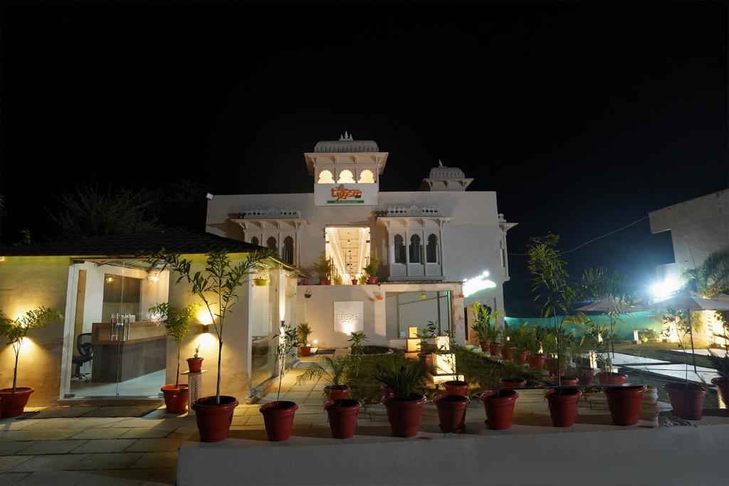 un grand bâtiment blanc avec une tour d'horloge la nuit dans l'établissement Tiger's Trail Hotel & Food Court, à Kumbhalgarh
