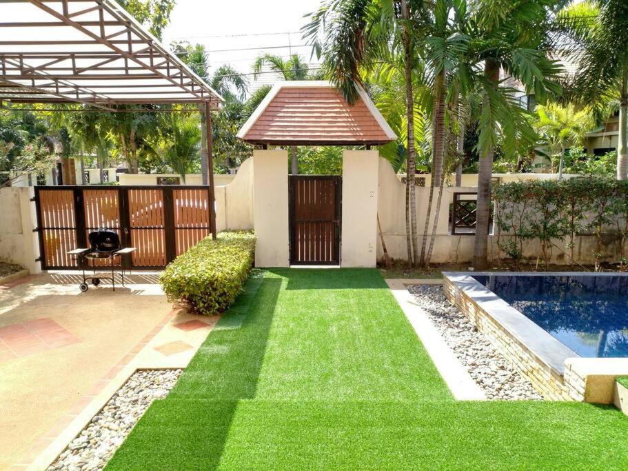 a yard with green grass and a swimming pool at Deluxe Pool Villa close to Beach and Walking Street! in Pattaya