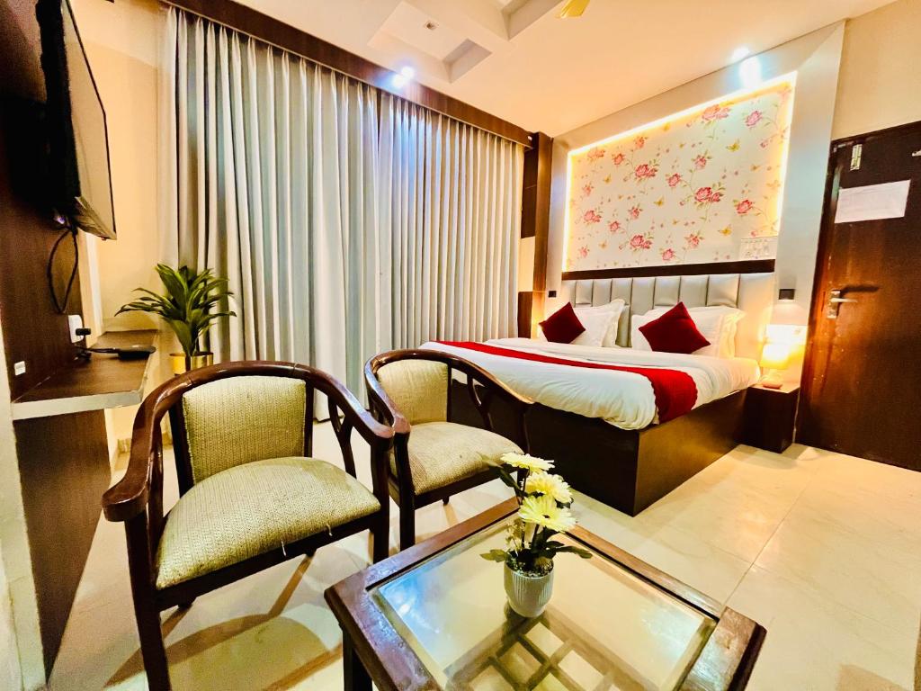 a hotel room with a bed and a table and chairs at The Ramawati - A Four Star Luxury Hotel Near Ganga Ghat in Haridwār