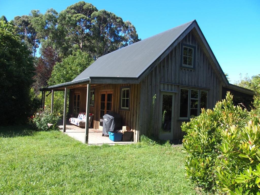una pequeña casa con techo de gambrel en un patio en Woodland eco retreat, en Parapara 