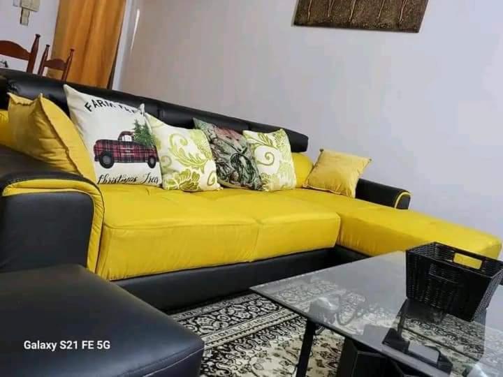 um sofá amarelo numa sala de estar com uma mesa em Entrée personnelle fidjrossè plage em Cotonou
