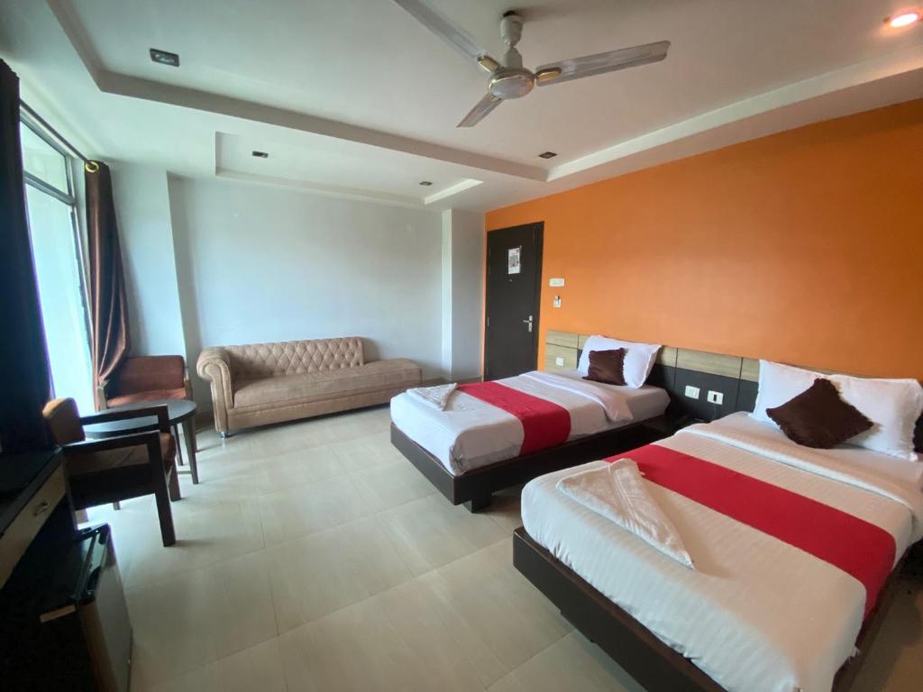 um quarto de hotel com duas camas e um sofá em Hotel Sunview Guwahati em Guwahati