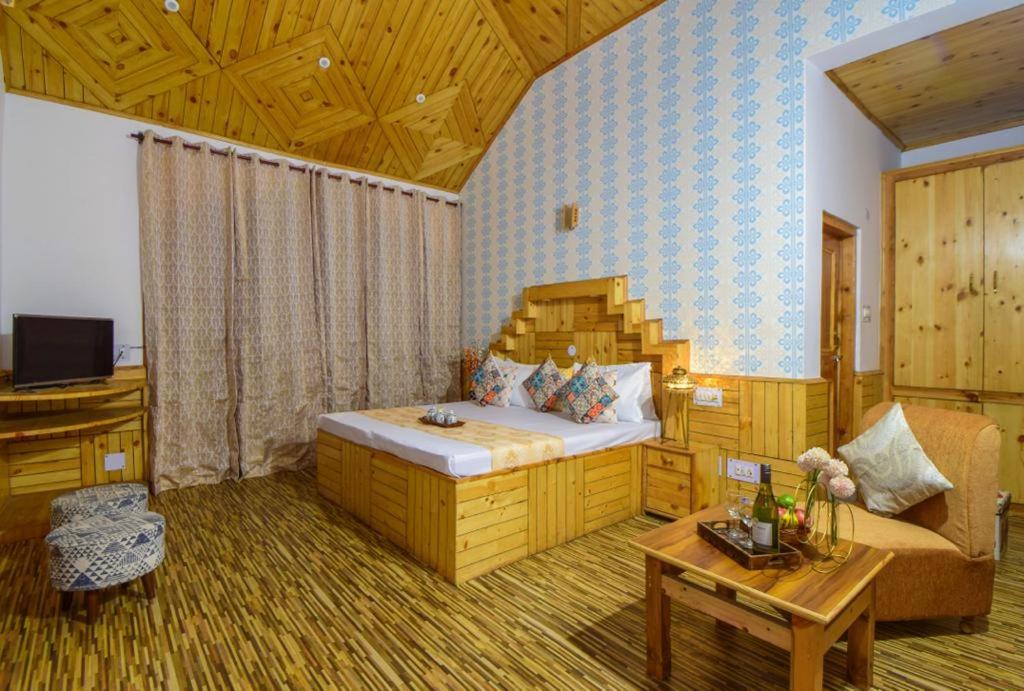 sypialnia z łóżkiem, kanapą i stołem w obiekcie Hotel Hadimba Manali By YB Hotels w mieście Manāli