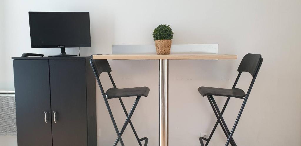 d'une table avec deux chaises et d'une télévision. dans l'établissement Alpine Stay - Studio Entier Résidence Standing vue parc au calme - Parking Gratuit - Wifi - Tram à proximité, à Grenoble