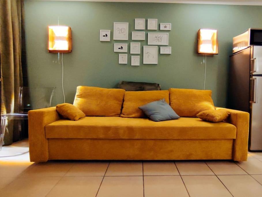 ein gelbes Sofa im Wohnzimmer mit zwei Lichtern in der Unterkunft 6 min zum Hauptbahnhof, kostenfrei parken, cozy in Mainz