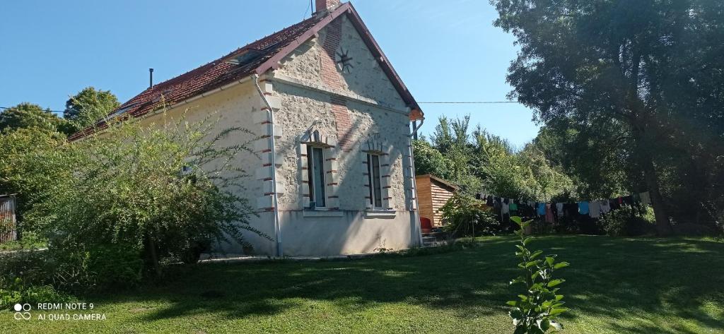 ein altes weißes Haus mit einer Wäscheleine im Hof in der Unterkunft Maison au bord d'un ruisseau in Pontigné